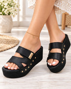 Sandalias Élara negras para mujer con plataforma, diseño de doble tira y detalles metálicos dorados.