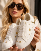 Tenis Aure Amore blancos para mujer con detalles dorados en forma de corazón y suela de plataforma.
